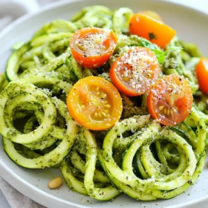 To make Pesto Parmesan Zucchini Noodles, gather these simple items: - 4 medium zucchinis - 1 cup fresh basil leaves, tightly packed - 1/4 cup pine nuts (or walnuts) - 1/2 cup freshly grated Parmesan cheese, plus extra for serving - 2 cloves garlic, peeled - 1/4 cup extra-virgin olive oil - Salt and freshly ground black pepper to taste - Handful of cherry tomatoes, halved (for garnish) You can swap ingredients if you like. Here are some ideas: - Use walnuts instead of pine nuts for a different flavor. - Try nutritional yeast if you want a vegan option for Parmesan cheese. - Use sunflower seeds in place of pine nuts for nut-free pesto. - If you can&rsquo;t find fresh basil, try spinach or arugula for a twist. For the best flavor, I recommend these brands: - Basil Pesto: Look for brands like Rao's or Barilla for high-quality options. - Parmesan Cheese: Grana Padano or Parmigiano-Reggiano are excellent choices. - Always choose freshly grated cheese for the best taste in your dish. {{ingredient_image_2}} To start, grab your medium zucchinis. Use a spiralizer to turn each zucchini into long noodles. If you lack a spiralizer, a vegetable peeler works as well. Just peel the zucchini and then slice it into noodle-like strips. Once done, place the noodles in a colander and sprinkle them lightly with salt. This helps remove extra moisture. Set them aside for a few minutes while you prep the pesto. Next, it's time to make the pesto. In a food processor, combine a cup of fresh basil leaves, 1/4 cup of pine nuts, and 1/2 cup of grated Parmesan cheese. Toss in two peeled garlic cloves too. Secure the lid and pulse until everything is finely chopped and blended. Now, while the processor runs, slowly drizzle in 1/4 cup of extra-virgin olive oil. Keep blending until the pesto is smooth and creamy. Taste it, and add salt and freshly ground black pepper if needed. Now, we mix the zucchini noodles with the pesto. In a large mixing bowl, add your prepared zucchini noodles. Pour the fresh pesto over the noodles. Gently toss everything together. You want all the noodles coated in that vibrant green sauce. Once mixed, it's time to serve! Portion the noodles onto plates and top with halved cherry tomatoes. A sprinkle of extra Parmesan cheese adds a nice finishing touch. Enjoy this light and flavorful meal! To craft the best pesto, use fresh basil leaves. They bring bright flavor. Always choose pine nuts for a rich taste. If you prefer, walnuts are a great substitute. When blending, add the olive oil slowly. This helps create a smooth texture. Taste your pesto as you go. Adjust with salt and pepper for balance. For zucchini noodles, start by spiralizing the zucchinis. A spiralizer makes perfect noodles. If you lack one, a vegetable peeler works too. Cut long strips into shorter pieces. After spiralizing, place the noodles in a colander. Sprinkle with salt to draw out moisture. Let them sit for a few minutes. This step ensures your dish won&rsquo;t be watery. Serving is key to a great meal. Portion the zucchini noodles on plates. Drizzle the pesto generously over the noodles. Add halved cherry tomatoes for color and flavor. Finish with a sprinkle of extra Parmesan cheese on top. For flair, add fresh basil leaves. A dash of cracked black pepper can brighten each dish. Pro Tips Use Fresh Ingredients: Always opt for fresh basil and high-quality olive oil to elevate the flavors of your pesto. Adjust the Thickness: If your pesto is too thick, add a little more olive oil or a splash of lemon juice to reach your desired consistency. Prevent Soggy Noodles: After salting the zucchini noodles, let them sit for a few minutes, then pat them dry to remove excess moisture. Experiment with Nuts: Feel free to substitute pine nuts with other nuts like walnuts or almonds for a different flavor profile in your pesto. {{image_4}} You can add protein to your Pesto Parmesan Zucchini Noodles for a heartier meal. Common choices include grilled chicken, shrimp, or tofu. Simply cook the protein of your choice and mix it in with the zucchini noodles. This will enhance the dish's flavor and make it more filling. If you prefer plant-based options, chickpeas or lentils are great alternatives. For a vegetarian twist, use more cheese or add a dollop of ricotta on top. If you're looking for vegan options, replace Parmesan with nutritional yeast. This will give a cheesy flavor without dairy. You can also make a nut-based cheese for a creamier texture. Add in some nuts or seeds for extra crunch and nutrition. Seasonal ingredients can elevate your dish. In summer, toss in fresh cherry tomatoes or bell peppers for color. In the fall, consider adding roasted butternut squash or mushrooms. These swaps keep your meal fresh and exciting. Always look for local produce to enhance flavor and support sustainability. To store leftover zucchini noodles, place them in an airtight container. Cover them tightly to keep moisture out. These noodles can last for about two days in the fridge. Be aware that they may lose some texture. If you want to keep them fresh longer, consider storing them without salt. Salt can draw out moisture and make them soggy. To freeze pesto, first pour it into ice cube trays. This method helps you use just the right amount later. Once the pesto is frozen, pop the cubes into a freezer bag. Label the bag with the date so you remember when you made it. Frozen pesto can last for up to three months. When you want to use it, thaw in the fridge overnight or microwave for a quick defrost. When reheating zucchini noodles, do it gently. Use a pan on low heat to warm them up. Add a splash of water or olive oil to prevent sticking. Stir them gently to avoid breaking the noodles. Heat for just a few minutes until warm. Avoid overheating, as this can make them mushy. If you&rsquo;re reheating pesto, warm it in a small pot on low heat, stirring often. This keeps the flavors bright and fresh. Yes, you can make zucchini noodles ahead. Prepare them and store in the fridge. Use a colander to drain excess water. This helps keep them from getting soggy. I suggest using them within one day for the best taste and texture. The best tool for spiralizing zucchini is a spiralizer. It quickly turns zucchini into noodles. You can find both handheld and countertop models. If you don&rsquo;t have a spiralizer, a vegetable peeler works great. It makes long strips that you can cut into noodle shapes. You can make pesto without pine nuts by using other nuts. Walnuts are a good substitute and add nice flavor. You can also use sunflower seeds for a nut-free option. Just blend them with basil, garlic, and cheese for a tasty result. In this post, I covered the essentials for making a great zucchini noodle dish. We explored key ingredients, including substitutions and brands. Next, I guided you through step-by-step instructions on preparing zucchini noodles and making pesto. I shared useful tips for cooking and serving. We also looked at variations, storage tips, and answered common questions. Final thoughts: Embrace creativity in your cooking. Enjoy experimenting with flavors and textures!